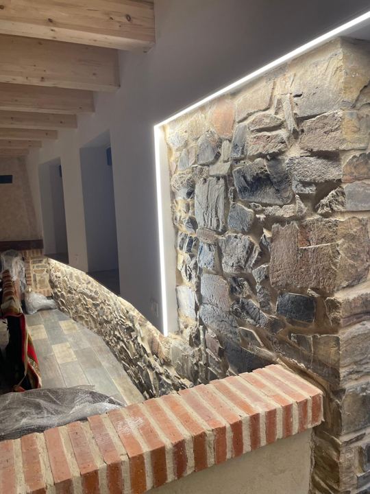 Tira LED que ilumina un muro de piedra en una vivienda